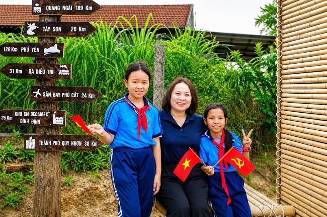 Bà Nguyễn Thị Thu Thủy – Bí thư Đảng ủy xã Canh Vinh cùng các em học sinh tại cổng làng Canh Tiến.